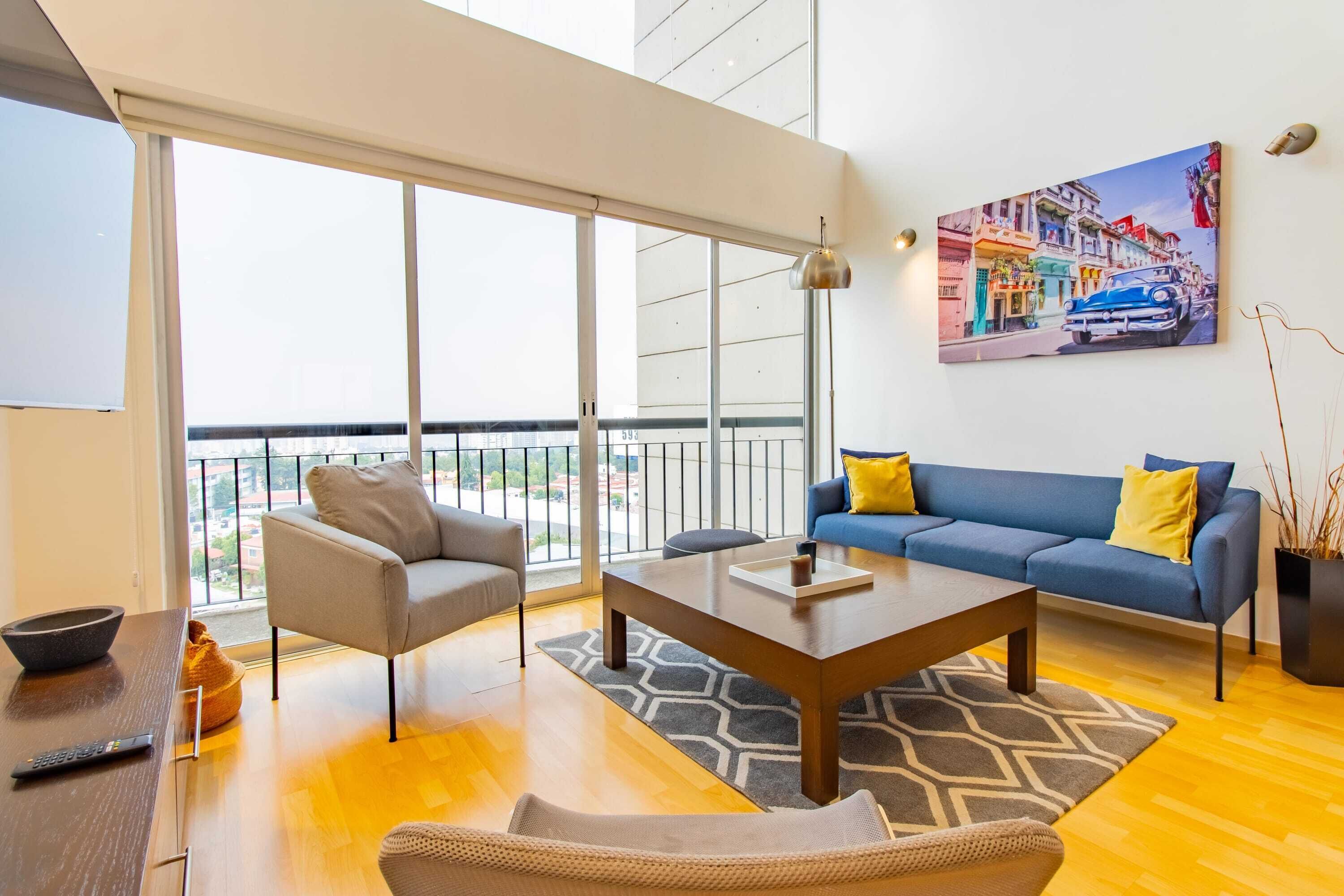 A modern living room with a sofa, armchair, coffee table, and a painting on the wall.