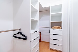 A walk-in closet with open shelves, a hanging rack, and a folded towel on a shelf. - Capitalia  Santa Fe Duplex w Gym & City View (Ciudad de México)