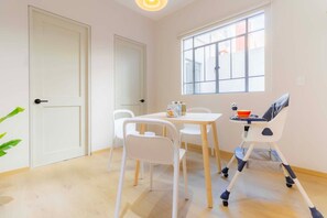 A bright room with a white door, a window, a table, chairs, and a high chair. - Capitalia , Nuevo Polanco, Patio & Pet Friendly (Ciudad de México)