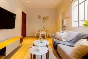 A modern living room with a flat-screen TV, a sofa, a coffee table, and a dining area with chairs and a table. - Capitalia , Nuevo Polanco, Patio & Pet Friendly (Ciudad de México)