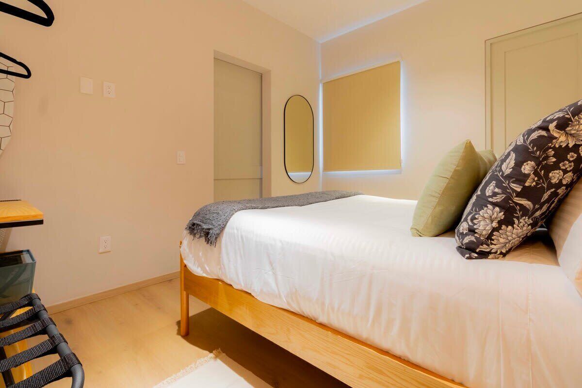 A bedroom with a bed, a desk, and a chair.