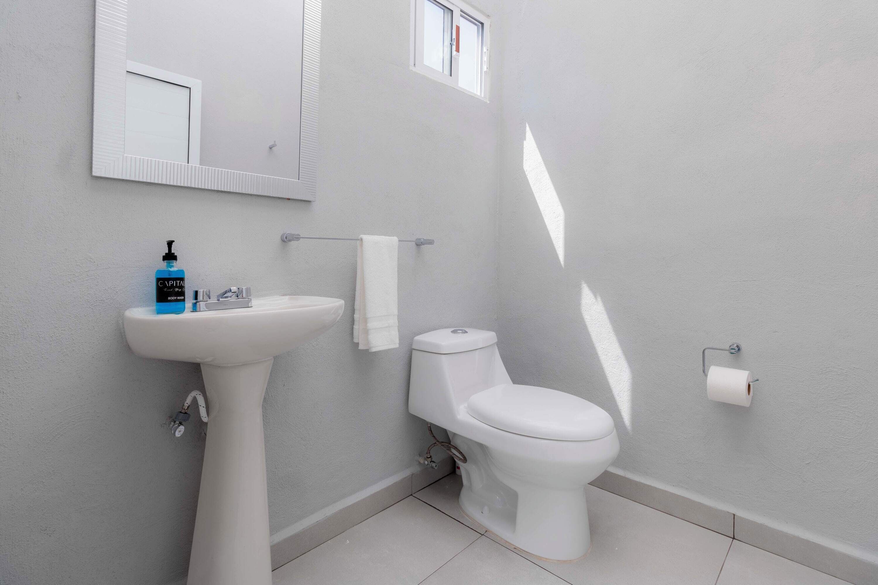 Ein Badezimmer mit einem weißen Waschbecken, einer Toilette und einem Spiegel an der Wand.