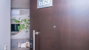 A hotel room with a door labeled 'b53', a bed, a bedside table, and a wall-mounted air conditioning unit. - Modern 2BR Apt with Balcony Free Parking B53 (Asunción)