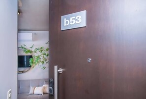 Ein Hotelzimmer mit einer Tür mit der Bezeichnung 'b53', einem Bett, einem Nachttisch und einer wandmontierten Klimaanlage.