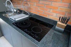 A kitchen with a black induction cooktop, a dish rack, and a knife block. - Modern 2BR Apt with Balcony Free Parking B53 (Asunción)