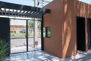 En modern byggnad med en fasad av tegel, stora glasdörrar och en överbyggd entré.