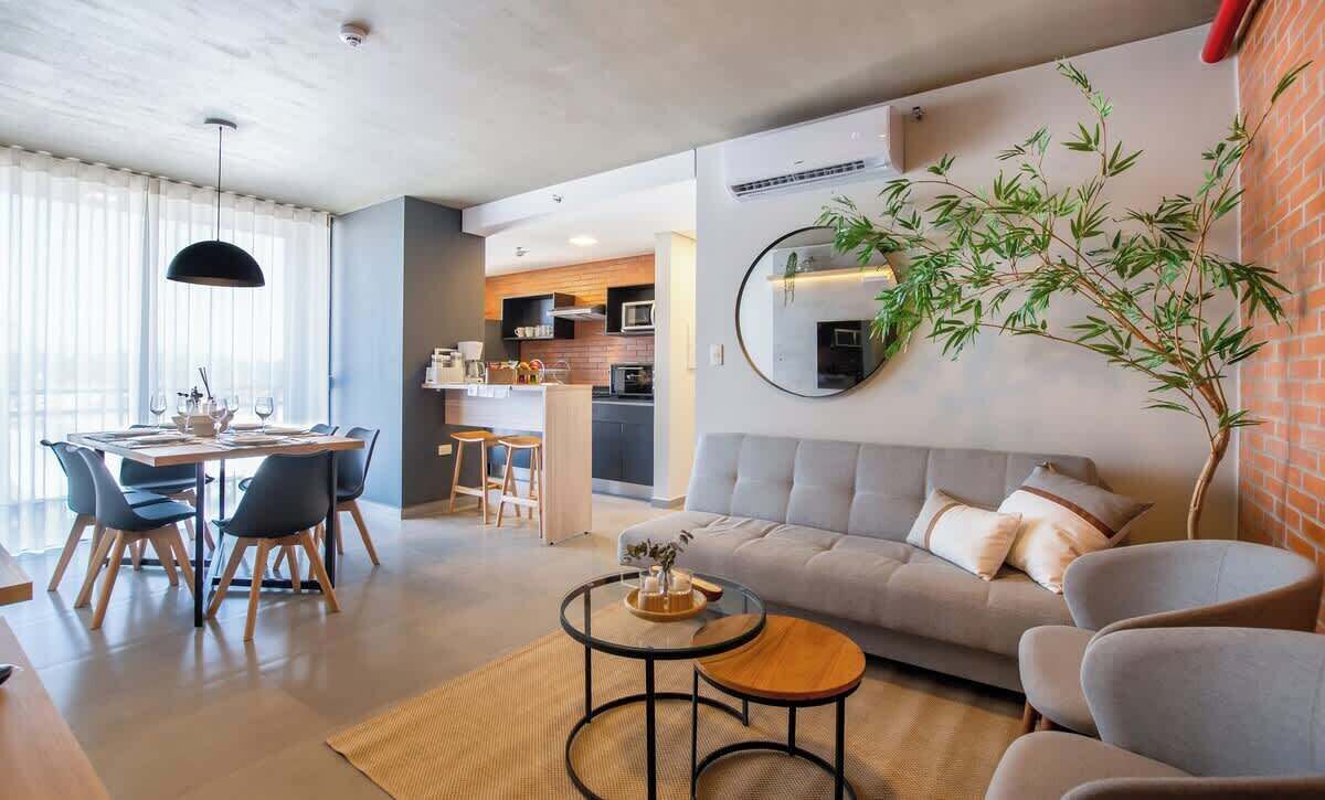 Una sala de estar moderna con un sofá, sillas, una mesa de comedor y una mesa auxiliar.