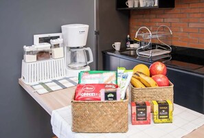 A kitchen counter with a coffee maker, jars, a basket of fruits, and packaged snacks. - Modern 2BR Apt with Balcony Free Parking B53 (Asunción)