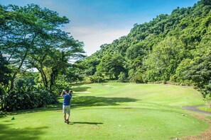 A golf course with lush greenery and a clear sky.