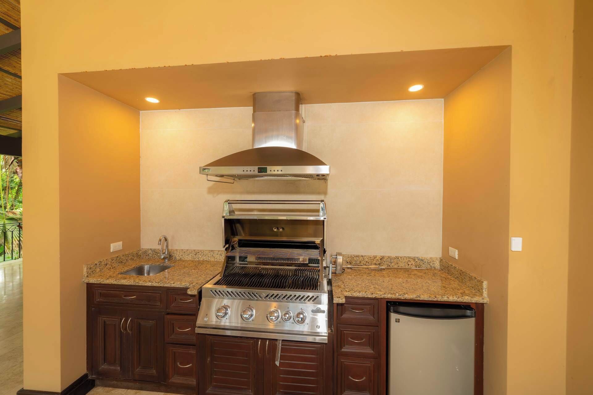 A compact kitchen with a built-in oven, a stainless steel range hood, and a dishwasher.