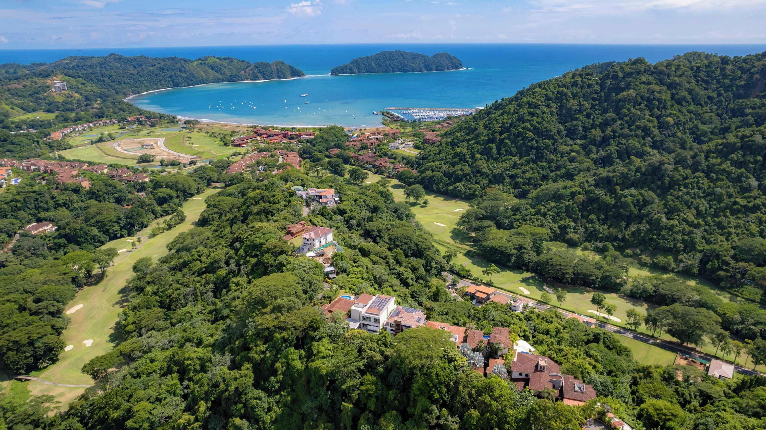 Una zona costanera amb edificis residencials, un camp de golf i un port esportiu.