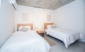 Ein Hotelzimmer mit zwei Betten, einem Nachttisch mit Lampe und einem Fenster.