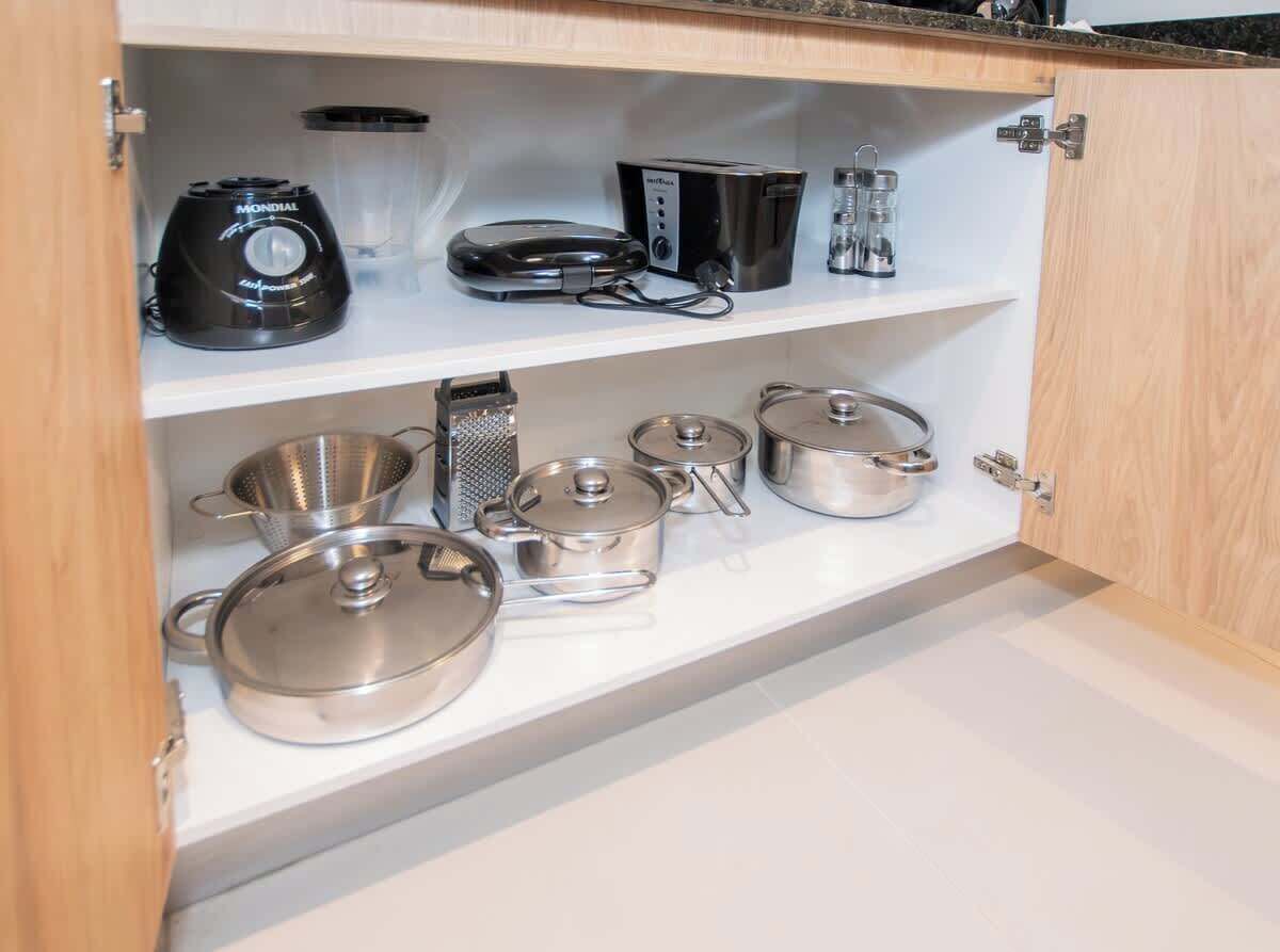A kitchen with a countertop, a coffee maker, a kettle, a grater, and several pots.