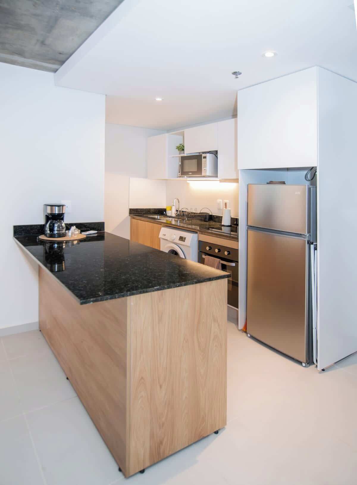 Une cuisine moderne dotée d’un îlot central, d’appareils électroménagers intégrés et d’un design minimaliste.