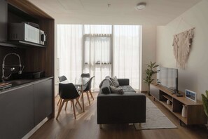 Ein modernes Wohnzimmer mit einer Couch, einem Fernseher und einem Essbereich.