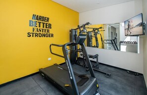 Une salle de sport équipée de tapis de course, d’appareils de musculation et ornée d’une citation motivante sur le mur.