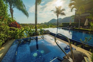 Une piscine bordée de carreaux, entourée d’une végétation luxuriante et de palmiers, offrant une vue dégagée sur le paysage environnant.