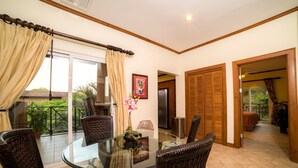 A dining area with a glass table, wicker chairs, and a view of the outdoors. - Veranda 5A - 1 bdr 1 bath (Playa Herradura)