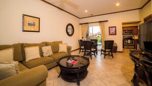 A living room with a sofa, a coffee table, a TV, and a dining area with chairs. - Veranda 5A - 1 bdr 1 bath (Playa Herradura)