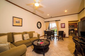 A living room with a sofa, a coffee table, a TV, and a dining area with chairs. - Veranda 5A - 1 bdr 1 bath (Playa Herradura)