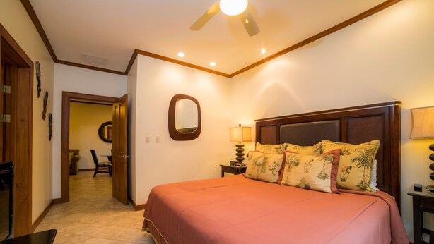 A hotel room with a bed, a nightstand, a lamp, and a ceiling fan. - Veranda 5A - 1 bdr 1 bath (Playa Herradura)