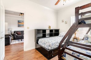 Ein Schlafzimmer mit Etagenbett, Schreibtisch, Stuhl und einer Couch.