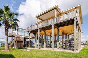 Une maison à deux étages située en bord de mer, dotée d’un balcon, d’un escalier et d’un espace piscine.