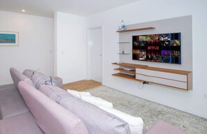 A modern living room with a flat-screen TV mounted on the wall, a sofa, and a coffee table. - Spacious 2BR Apt with Crib and Office Walk to Malls (Asunción)
