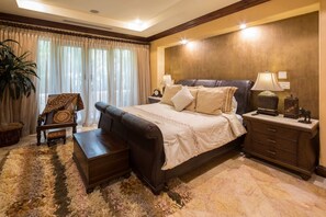 Un dormitorio con una cama grande, una mesita de noche, una lámpara, una silla y una planta de gran tamaño.