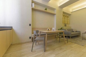 A modern living room with a dining table, chairs, a sofa, and a small plant. - HOM 2B Capitalia Palacio Polanco 2BR Prime (Ciudad de México)