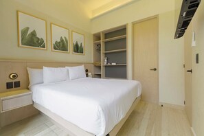 Ein Hotelzimmer mit Bett, Nachttisch, Wandbild und integrierten Regalen.