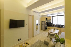 A modern apartment with a flat-screen TV, a dining area, a kitchen with a microwave, and a large window. - HOM 2B Capitalia Palacio Polanco 2BR Prime (Ciudad de México)