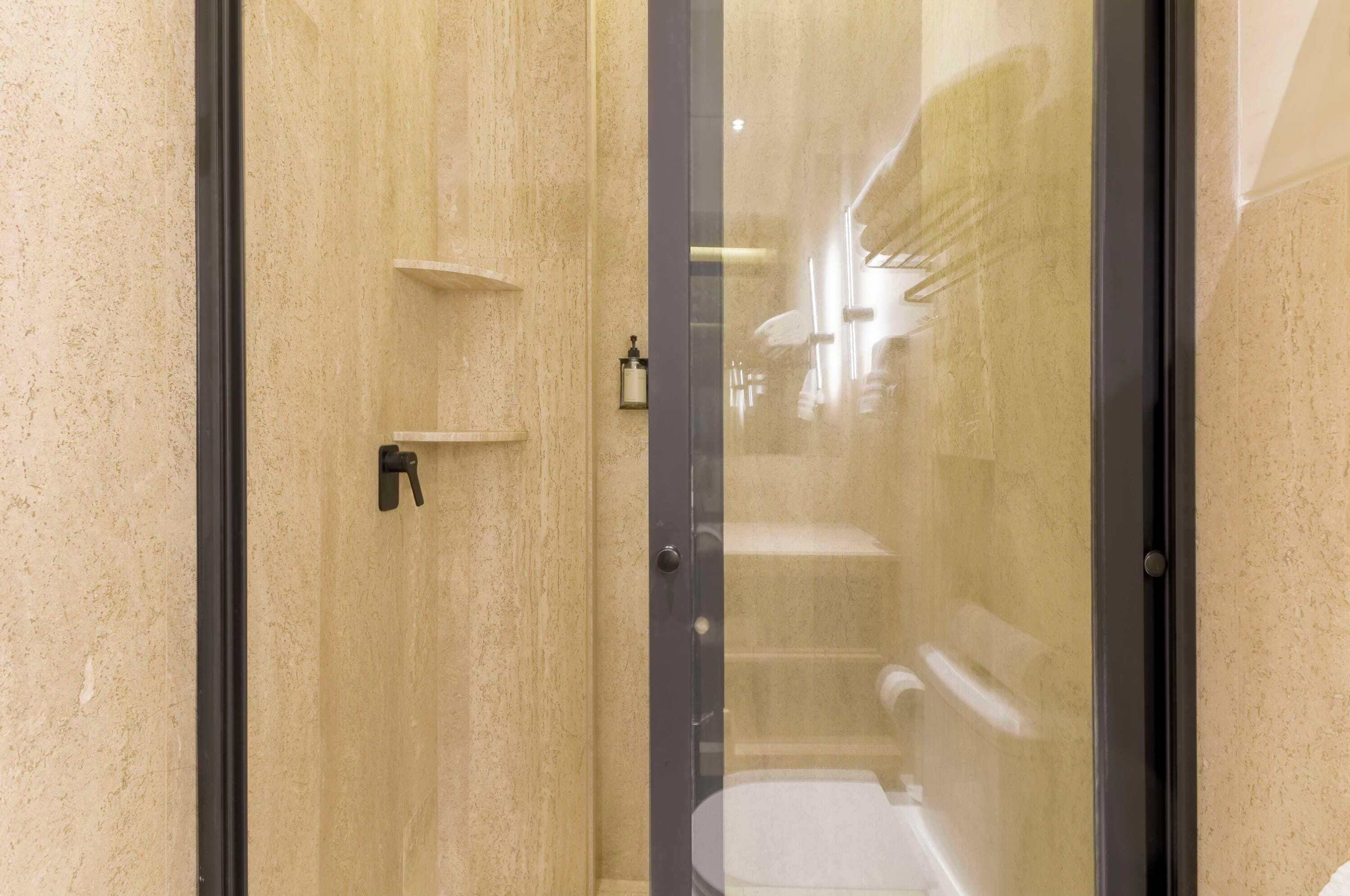 Une salle de bain moderne avec une douche à parois de verre, un porte-serviettes et un distributeur de savon fixé au mur.