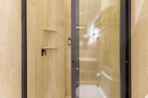 Une salle de bain moderne avec une douche à parois de verre, un porte-serviettes et un distributeur de savon fixé au mur.