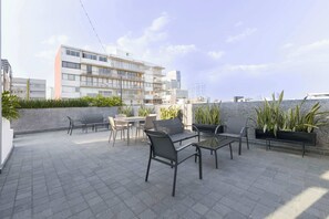 An outdoor patio area with a table and chairs, a sofa, and potted plants. - HOM 2B Capitalia Palacio Polanco 2BR Prime (Ciudad de México)