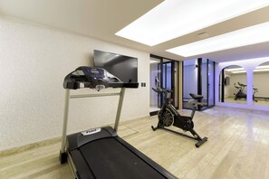 A gym with a treadmill, stationary bike, and a television on the wall. - HOM 2B Capitalia Palacio Polanco 2BR Prime (Ciudad de México)