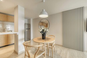 Eine moderne Küche mit Holzschränken, einem Edelstahlkühlschrank und einem runden Esstisch mit Stühlen.