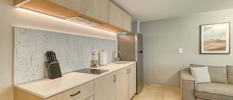 A modern kitchen with a countertop, sink, and stainless steel refrigerator.