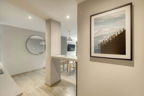 A modern kitchen with a dining area, a round mirror, and a framed landscape painting. - Modern King Studio in Central Roma Norte (Ciudad de México)