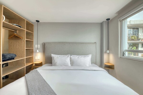Ein modernes Hotelzimmer mit einem großen Bett, einem Holzschrank, Nachttischen und einem Fenster mit Blick.