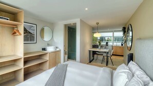 Een moderne hotelkamer met een bed, een houten garderobe, een badkamer en een zithoek.