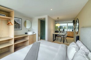 A modern hotel room with a bed, a wooden wardrobe, a bathroom, and a dining area. - Modern King Studio in Central Roma Norte (Ciudad de México)