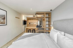 A modern hotel room with a bed, a built-in desk with a chair, a TV, and a wardrobe. - Modern King Studio in Central Roma Norte (Ciudad de México)