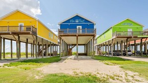 Een strandpand met drie gebouwen, elk voorzien van een balkon en een houten terras.