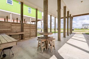 Un espace extérieur abrité, doté de bancs et d’une table en bois, soutenus par des piliers en bois, et surmonté d’un auvent blanc.