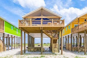 Une propriété située en bord de mer, dotée d’une terrasse en bois, d’un espace salon extérieur et d’une zone abritée.