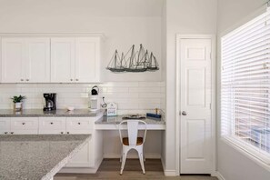A kitchen with white cabinets, a countertop, a coffee maker, a chair, and a decorative sailboat. - Beachfront, Views, 3bdr 2bth - The Bleu Pearl (Bolivar Peninsula)