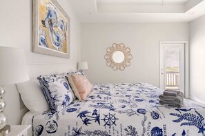 A bedroom with a bed, a painting, a mirror, and a door. - Beachfront, Views, 3bdr 2bth - The Bleu Pearl (Bolivar Peninsula)