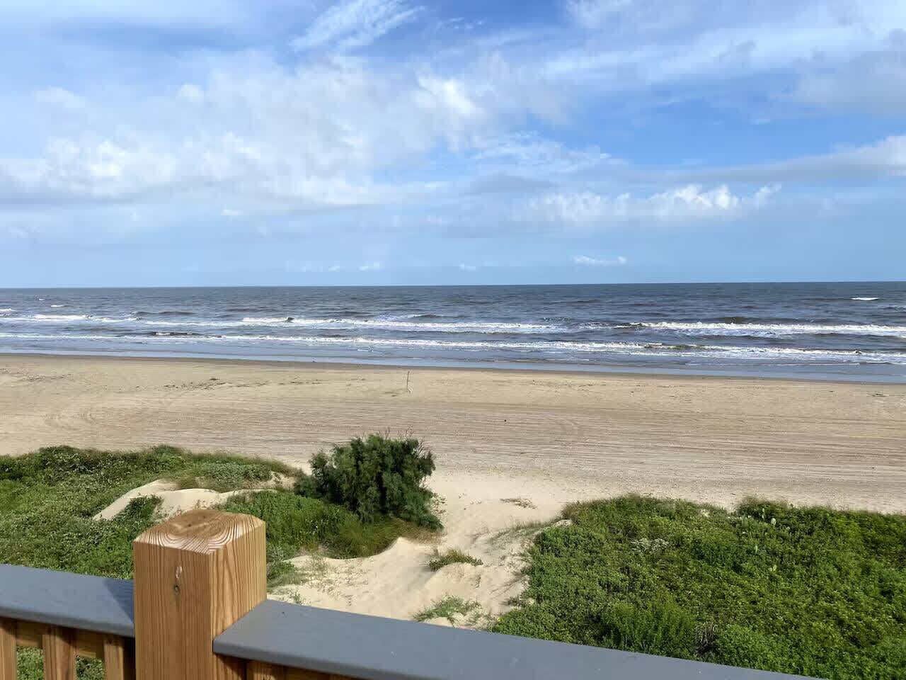 A beach with a wooden deck overlooking the ocean.