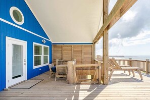 Un espace extérieur abrité doté d’une terrasse en bois, d’une table avec des chaises et d’une vue sur l’océan.